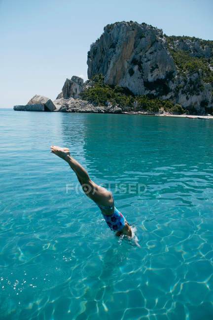 Mujer sumergiéndose en agua azul desde el barco - foto de stock