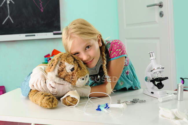Portrait de fille prétendant être vétérinaire étreignant tigre jouet avec goutte à goutte intraveineuse — Photo de stock