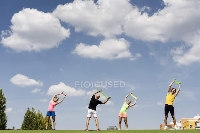 Four people training with rubber exercise bands — Stock Photo