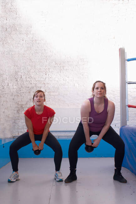 Femme faisant de l'exercice avec un entraîneur en salle de gym — Photo de stock