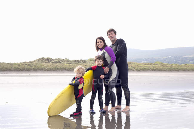 Famiglia con due ragazzi e tavola da surf in spiaggia — Foto stock