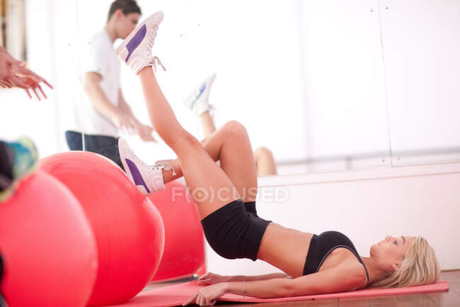 Jovem no ginásio treinamento de piso com bolas de exercício — Fotografia de Stock