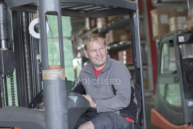Worker driving forklift truck in hardware store warehouse — Stock Photo