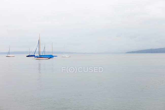Sailboats on still ocean under cloudy sky — Stock Photo