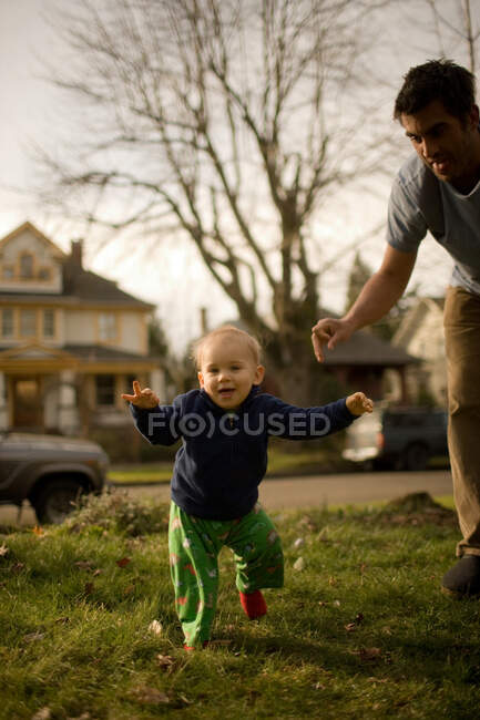 Padre con hijo dando los primeros pasos - foto de stock