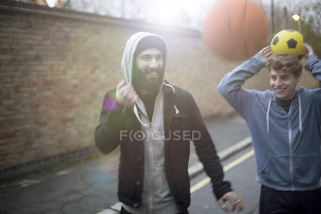 Dois homens andando na rua, segurando futebol — Fotografia de Stock