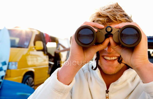 Man on beach with binoculars smiling — Stock Photo