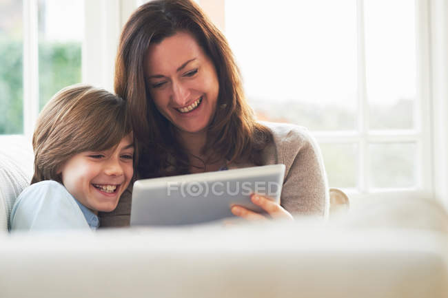 Mother and son on sofa using digital tablet — Stock Photo