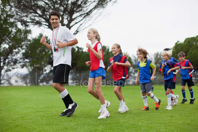 Coach training children on field — Stock Photo