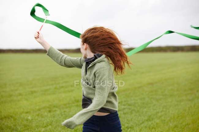 Дівчина-підліток грає зі стрічкою, вибірковий фокус — стокове фото