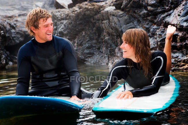 Couple lying on surfboards in the water — Stock Photo