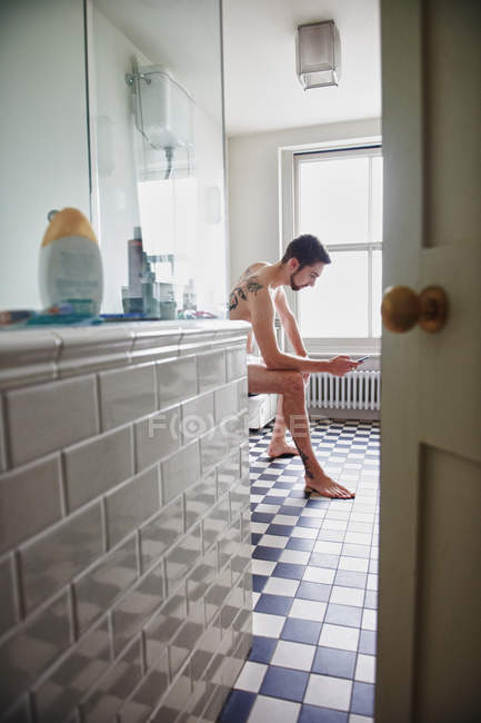 Nackter Mann benutzt Handy im Badezimmer — Stockfoto