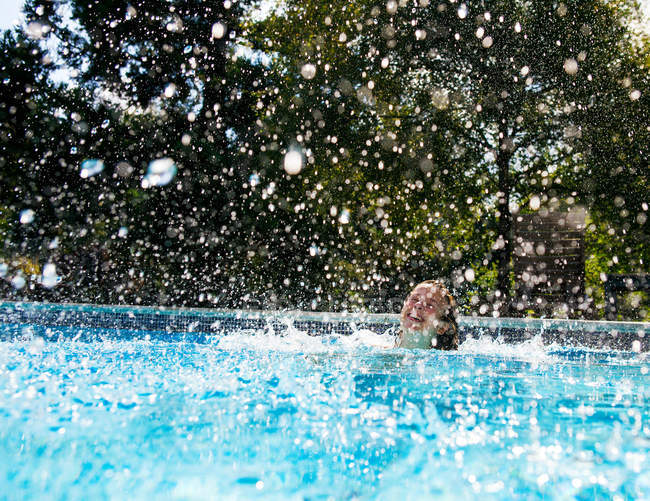Girl splashing in swimming pool — Stock Photo