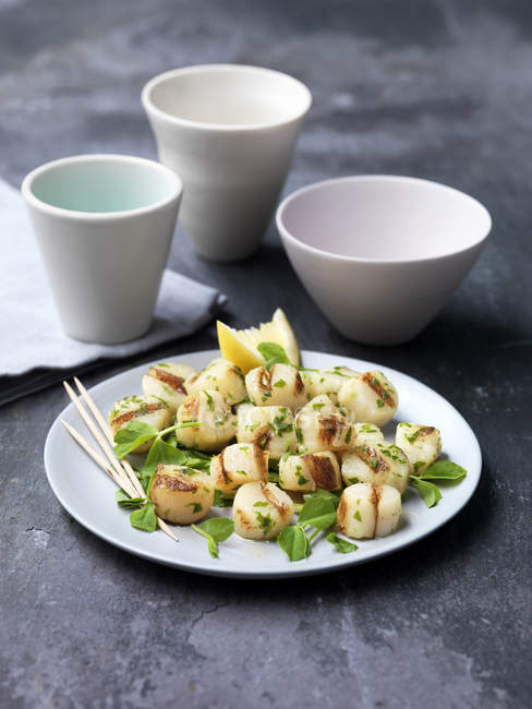 Chargrilled scallops on plate with herbs and lemon slice — Stock Photo