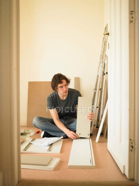 Hombre construcción de muebles flatpack - foto de stock