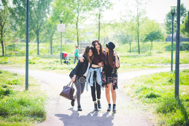 Троє молодих друзів прогулюються разом у парку — стокове фото