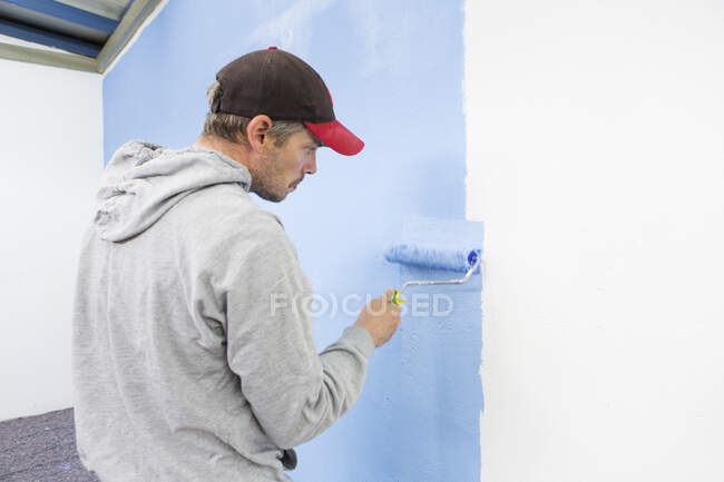 Vista posteriore di uomo pittura muro blu — Foto stock