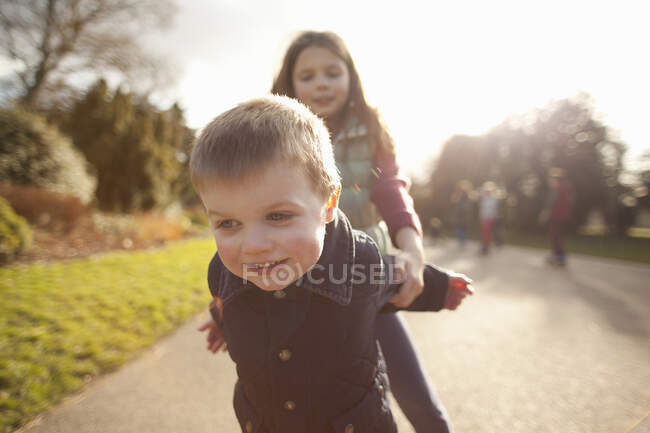 Niño y hermana jugando en el parque - foto de stock