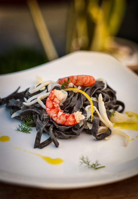 Black tagliatelle and prawns served on plate — Stock Photo