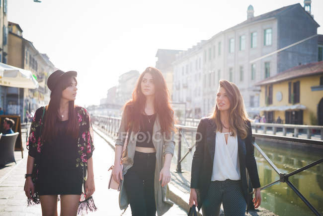 Троє молодих стильних жінок, що гуляють на набережній каналу — стокове фото
