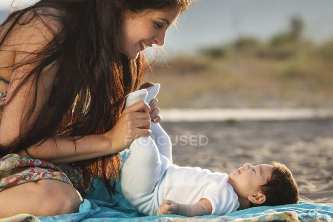 Madre mirando al bebé acostado en la alfombra - foto de stock