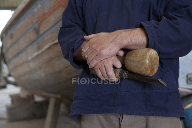 Close up of carpenters hands holding chisel in boat workshop — Stock Photo