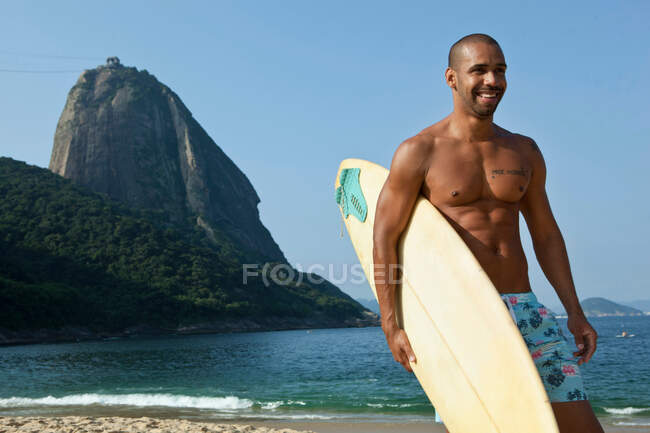 Мужчина с доской для серфинга на пляже, Рио-де-Жанейро, Бразилия — стоковое фото