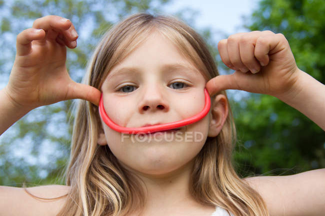 Retrato de menina fazendo rosto com alcaçuz — Fotografia de Stock
