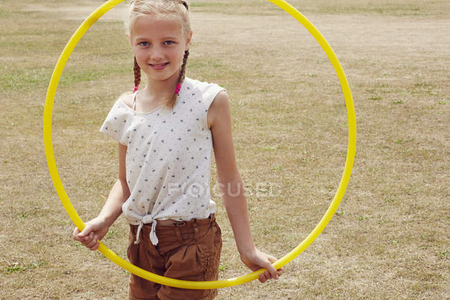Menina olhando através de hula hoop sorrindo para a câmera — Fotografia de Stock