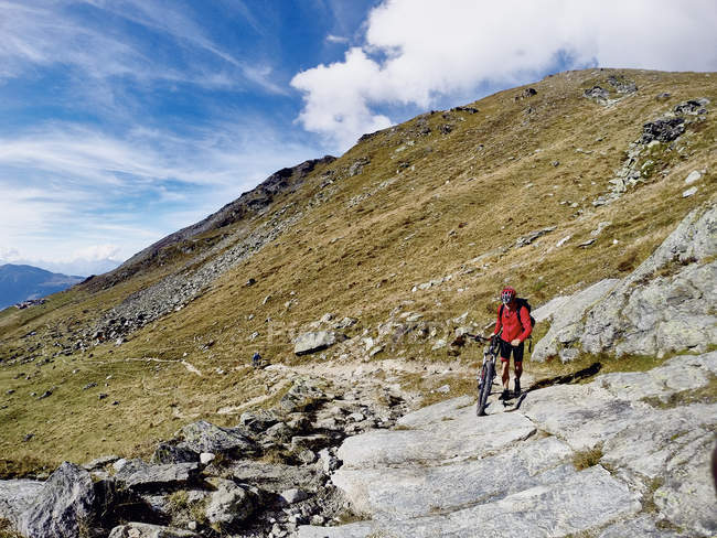 Mountainbiker schiebt Fahrrad über Felsen, Wallis, Schweiz — Stockfoto