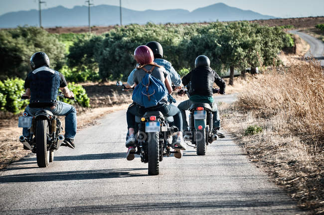 Rear view of four friends motorcycling on rural road, Cagliari, Sardinia, Italy — Stock Photo