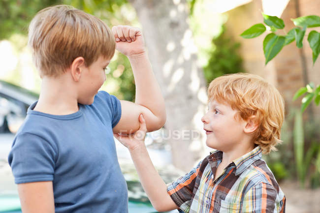 Junge fühlt Brüder Bizeps im Freien — Stockfoto