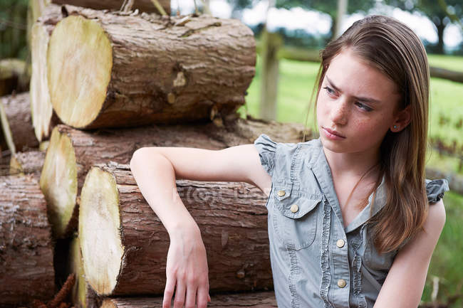 Adolescente se apoiando em logs na floresta — Fotografia de Stock
