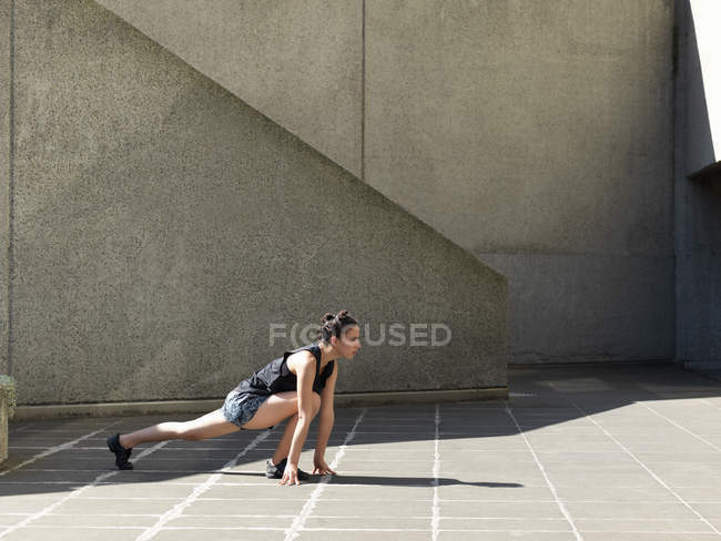 Mujer joven estirándose frente a la pared de hormigón - foto de stock