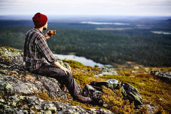 Male hiker overlooking landscape with coffee, Lapland, Finland — Stock Photo