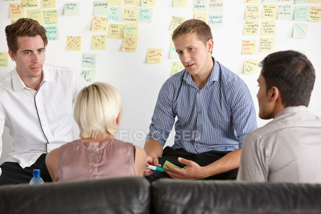 Cuatro colegas diseñadores discutiendo en la sala de reuniones - foto de stock
