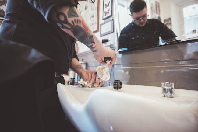Peluquero preparando cepillo de afeitar en peluquería fregadero - foto de stock