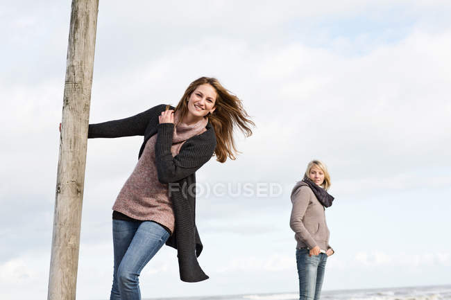 Woman swinging from pole on beach — Stock Photo