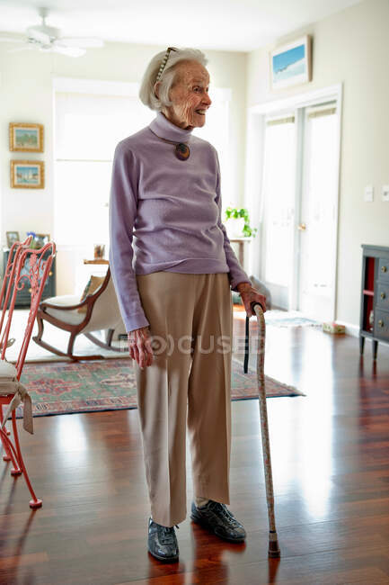 Mujer mayor parada en su sala de estar - foto de stock