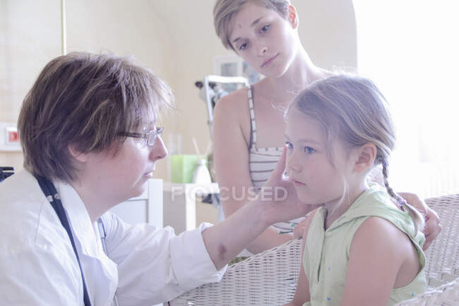 Docteur examinant fille, mère regardant — Photo de stock