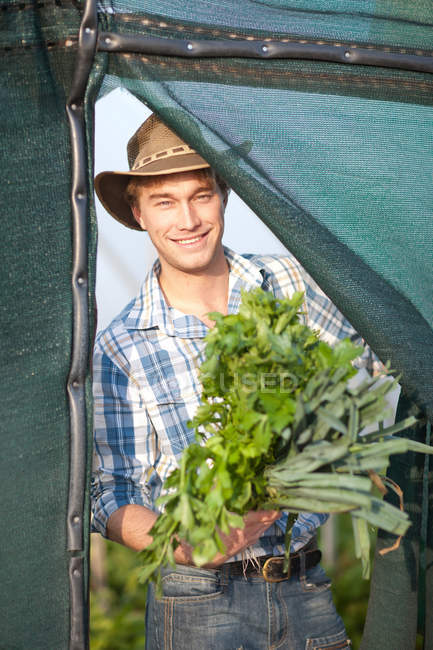 Joven con verduras cultivadas en la granja - foto de stock