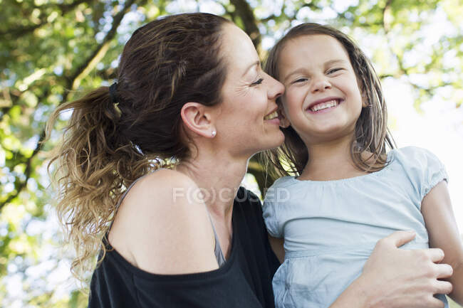 Madura mujer y hija riéndose en parque - foto de stock