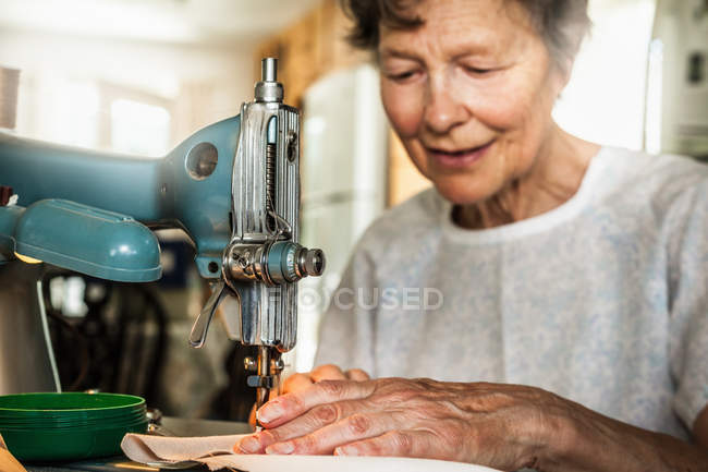 Ältere Frau arbeitet an Nähmaschine — Stockfoto