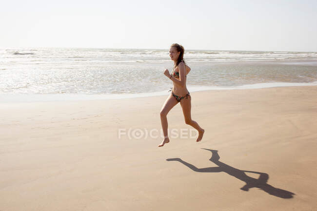 Дівчина-підліток біжить уздовж пляжу — стокове фото