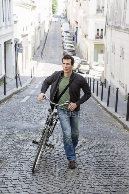 Metà uomo adulto spingendo bicicletta fino acciottolato strada della città — Foto stock