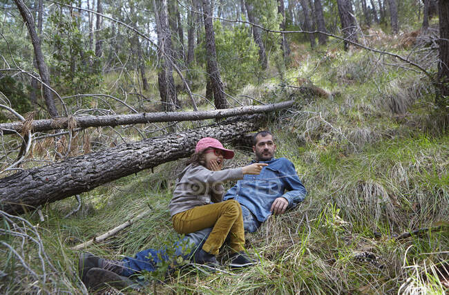 Mid adult man relaxing with daughter in forest — Stock Photo