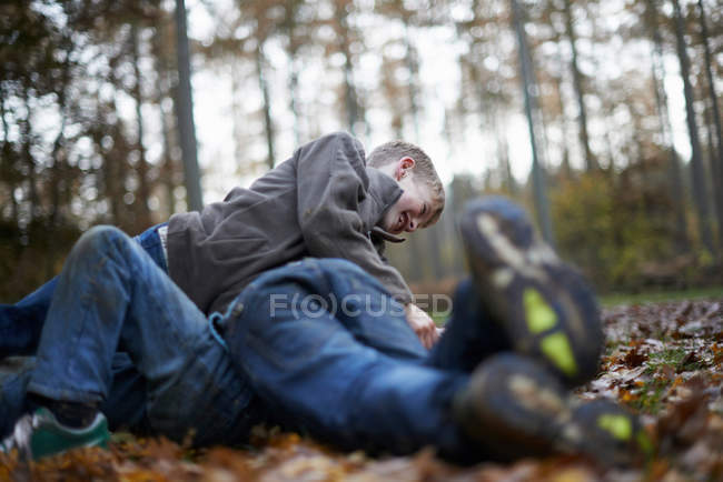 Jungen spielen Kampf auf Waldboden im Herbst — Stockfoto