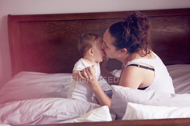 Mãe e bebê menino brincando na cama — Fotografia de Stock