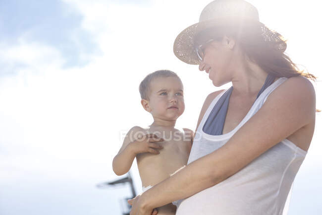 Madre llevando hijo en brazos - foto de stock