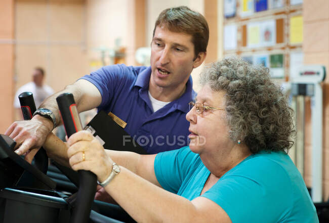 Entrenador ayudando a las mujeres mayores ejercicio - foto de stock